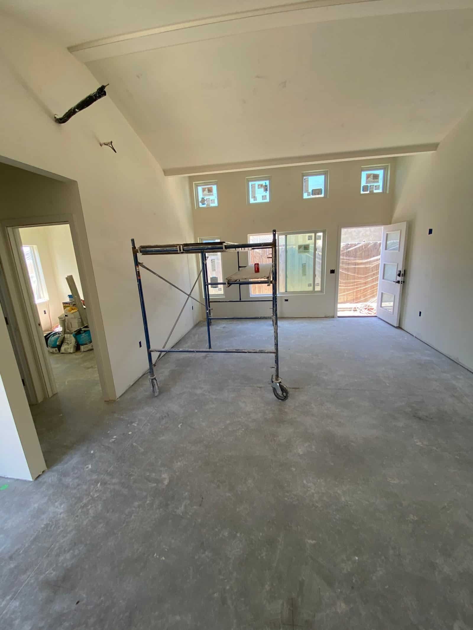 Interior drywall installation in progress with scaffolding in a new home.
